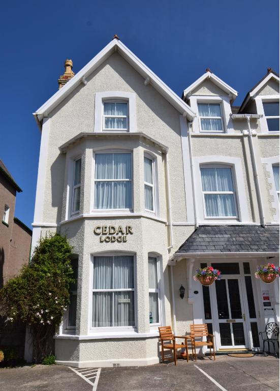 a white building with chairs in front of it at Cedar Lodge in Llandudno