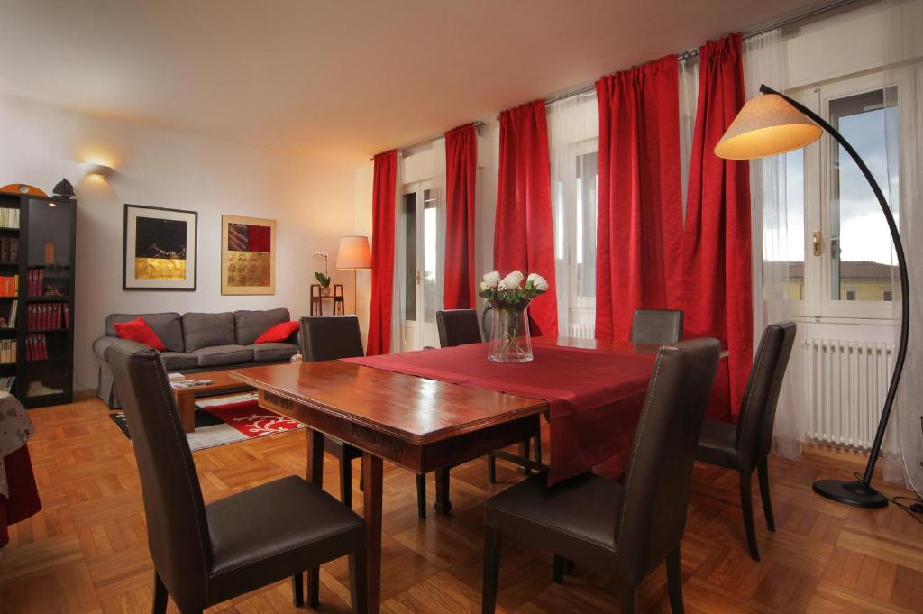 sala de estar con mesa de madera y cortinas rojas en B&B Al Parco Giardini Margherita, en Bolonia