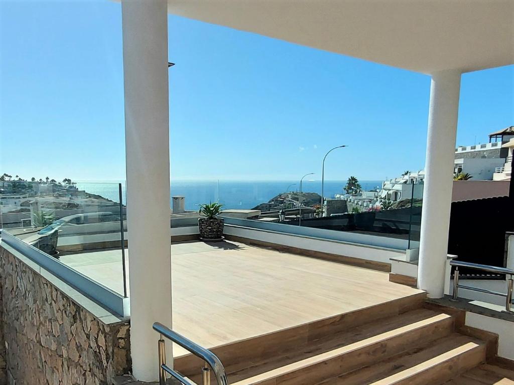 a balcony with stairs and a view of the ocean at Villa Playa Amadores - Luxury villa with heated pool in Puerto Rico de Gran Canaria