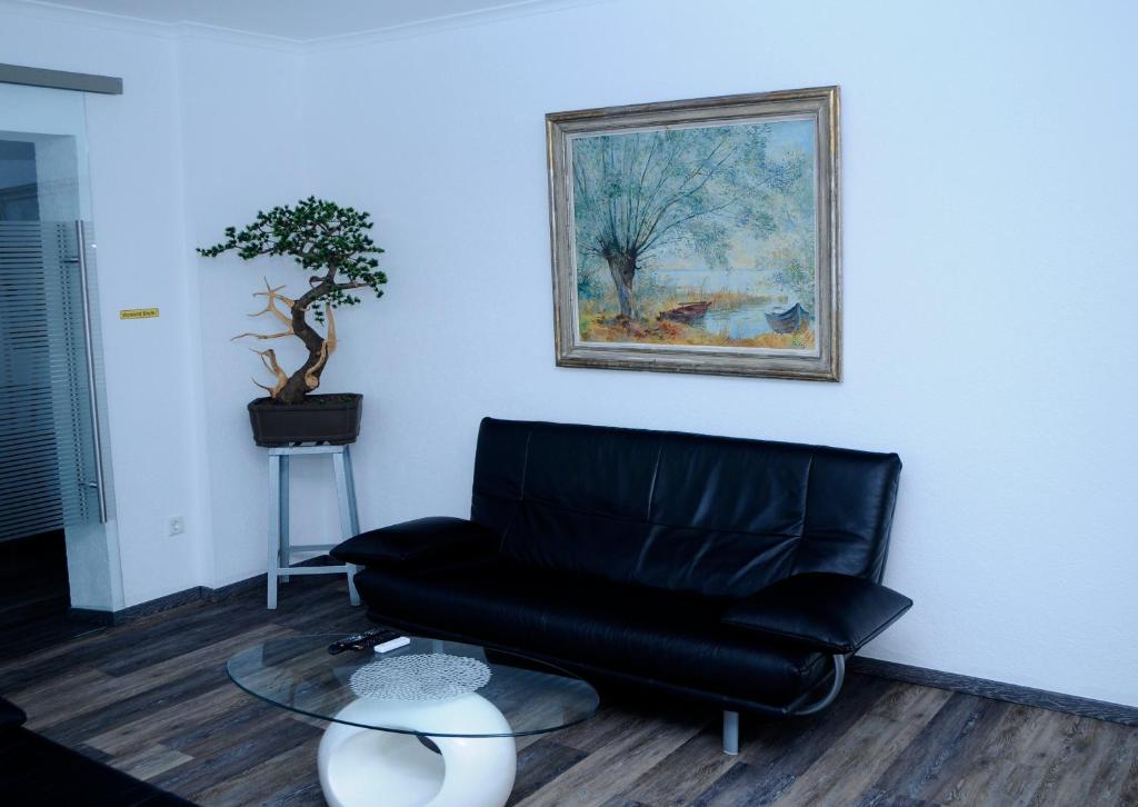 ein Wohnzimmer mit einem schwarzen Ledersessel und einem Gemälde in der Unterkunft Bonsai-Ferienwohnung in Bad Laer