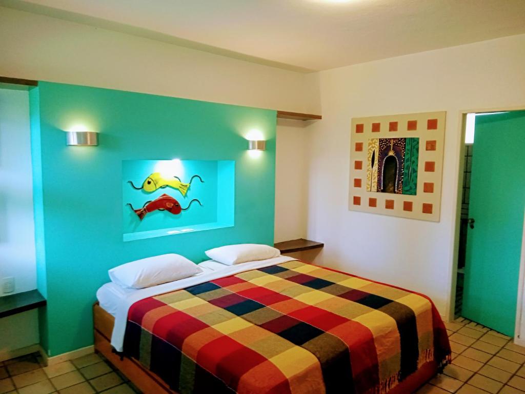a bedroom with a bed with a colorful blanket at Pousada Marahú in Porto De Galinhas