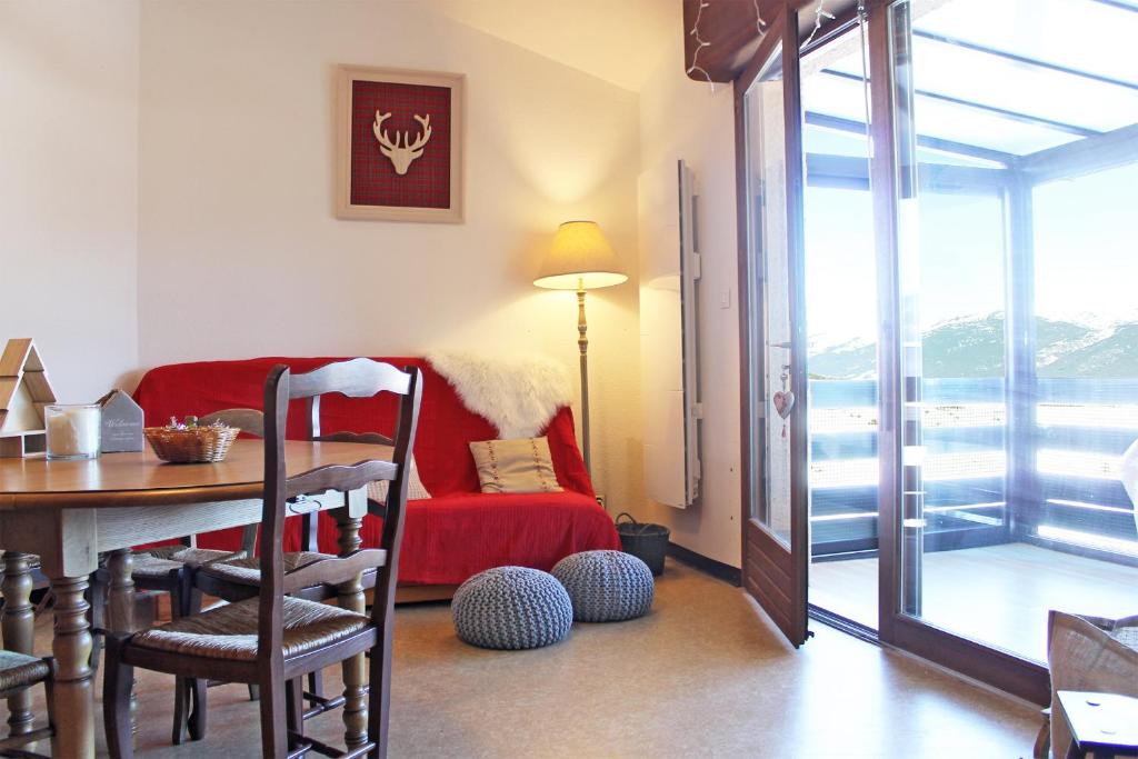 ein Wohnzimmer mit einem Tisch und einem roten Sofa in der Unterkunft Duplex sur le lac Les Angles 7 personnes in Les Angles