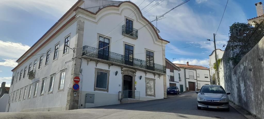 a white building with a car parked in front of it at Hotel Abade João in Montemor-o-Velho