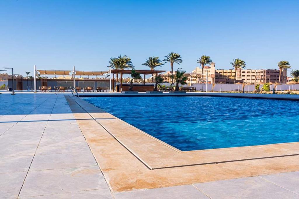 uma grande piscina com palmeiras e edifícios em The Comfortable palace em Hurghada