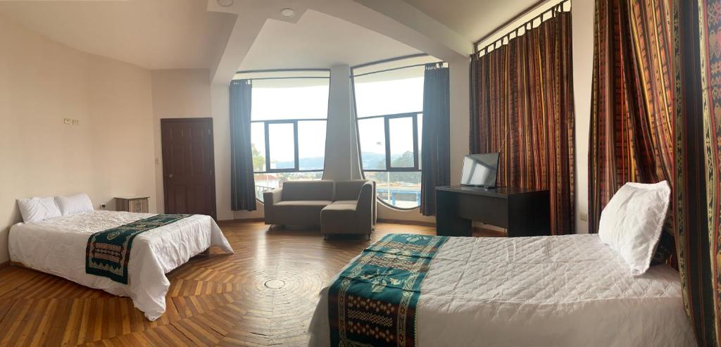 una camera d'albergo con due letti e una sedia e finestra di Hotel Chasky Cuenca a Cuenca
