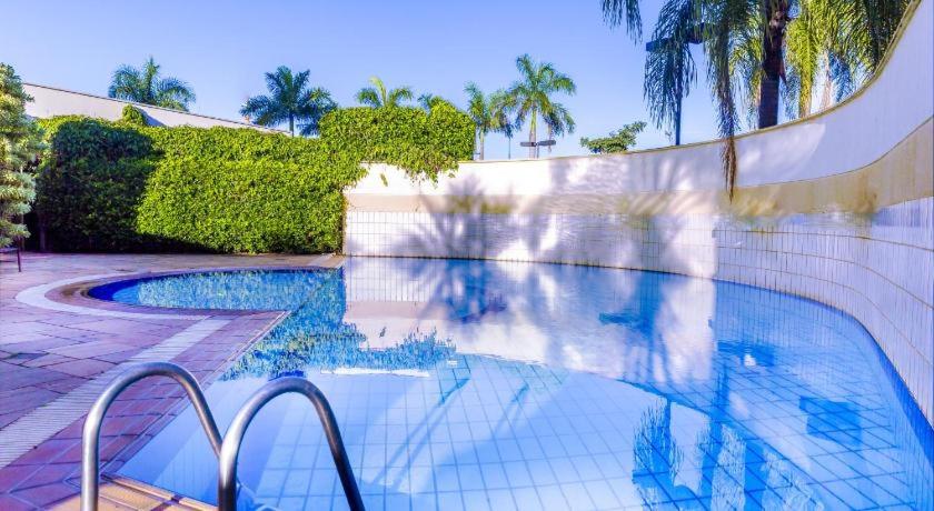 a swimming pool with a fence and palm trees at Flat em Franca SP in Franca