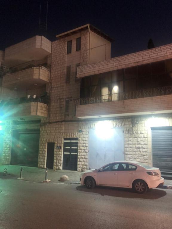 a white car parked in front of a building at night at Hassan Guesthouse in Nazareth