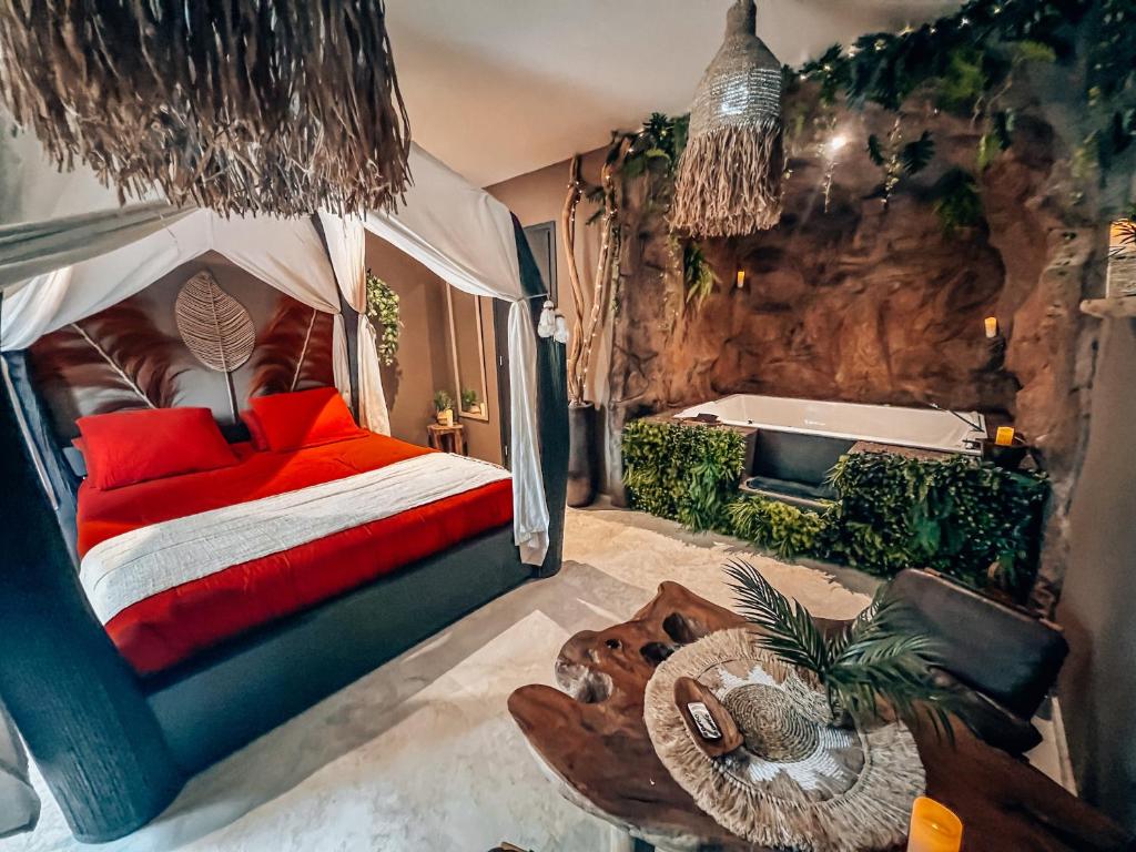 a bedroom with a bed with red pillows and a tub at Le demeure de Poulpican chambre LA GROTTE jacuzzi charme romantique terrasse privée 300m plage et restaurants La Croix Valmer - Golfe Saint Tropez in La Croix-Valmer