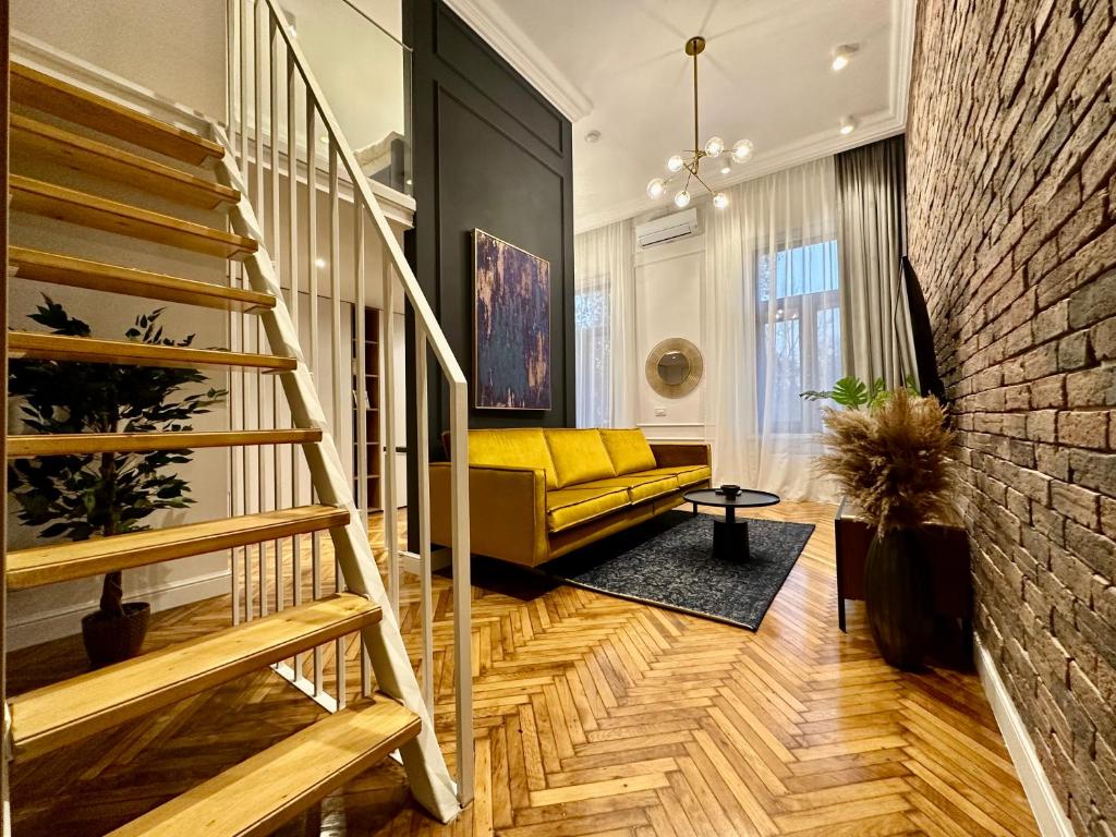 a living room with a yellow couch and a staircase at Olimpia Residence Palace Oradea in Oradea