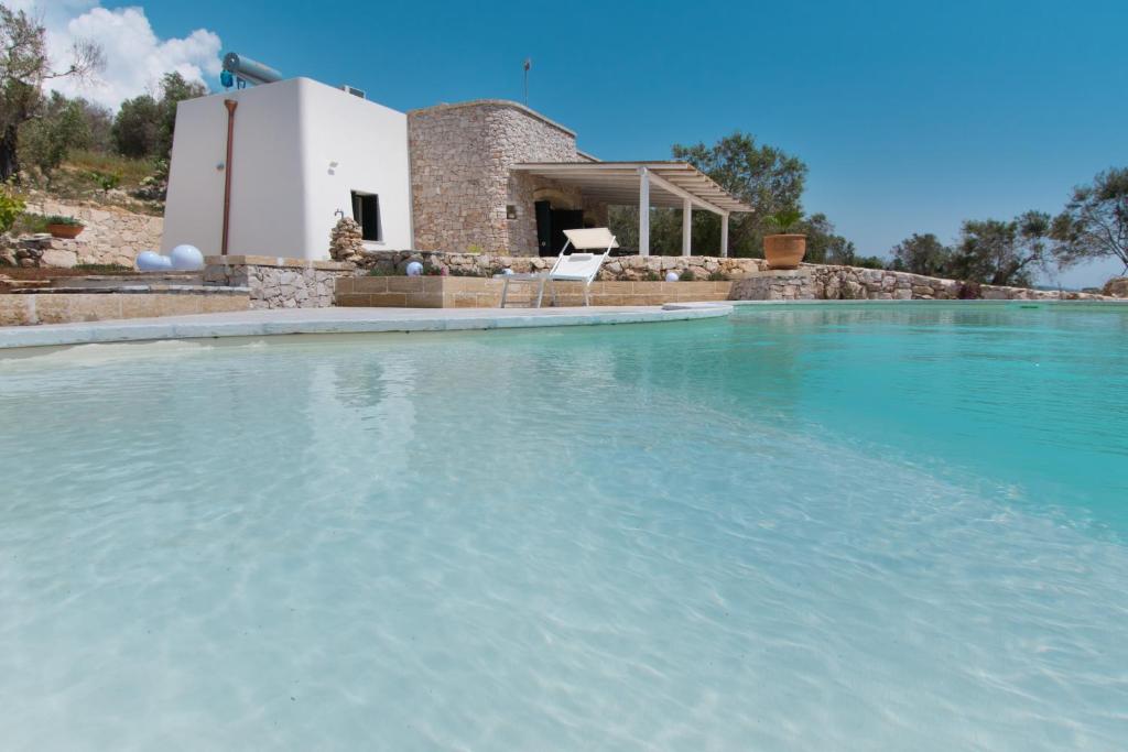 una grande piscina di acqua blu di fronte a una casa di VILLA Alessandra a Marina di Pescoluse