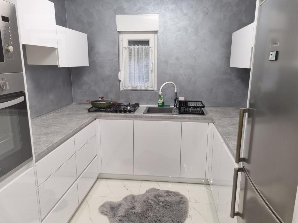 a kitchen with white cabinets and a sink at Kuća za odmor Rita in Čepin