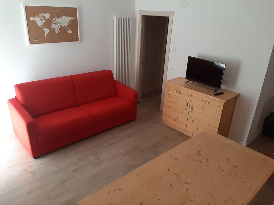 sala de estar con sofá rojo y TV en Appartamento nel Cuore della Val di Sole, en Dimaro