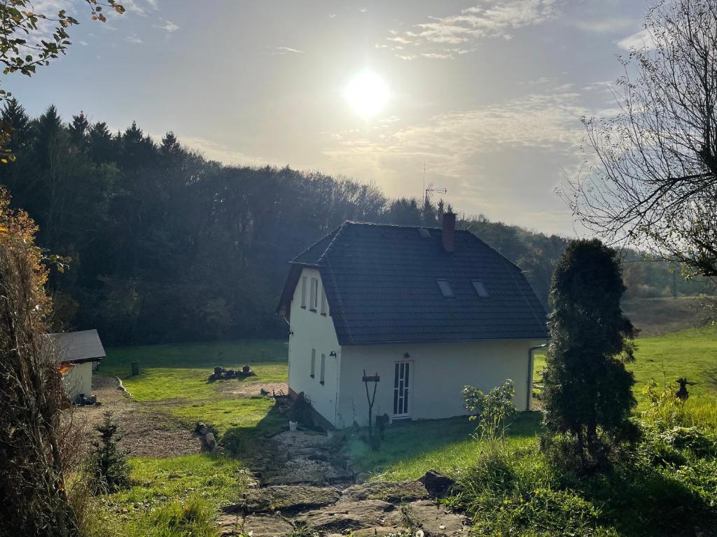 Una casa blanca en un campo con el sol detrás. en Veselka en Dolní Bousov