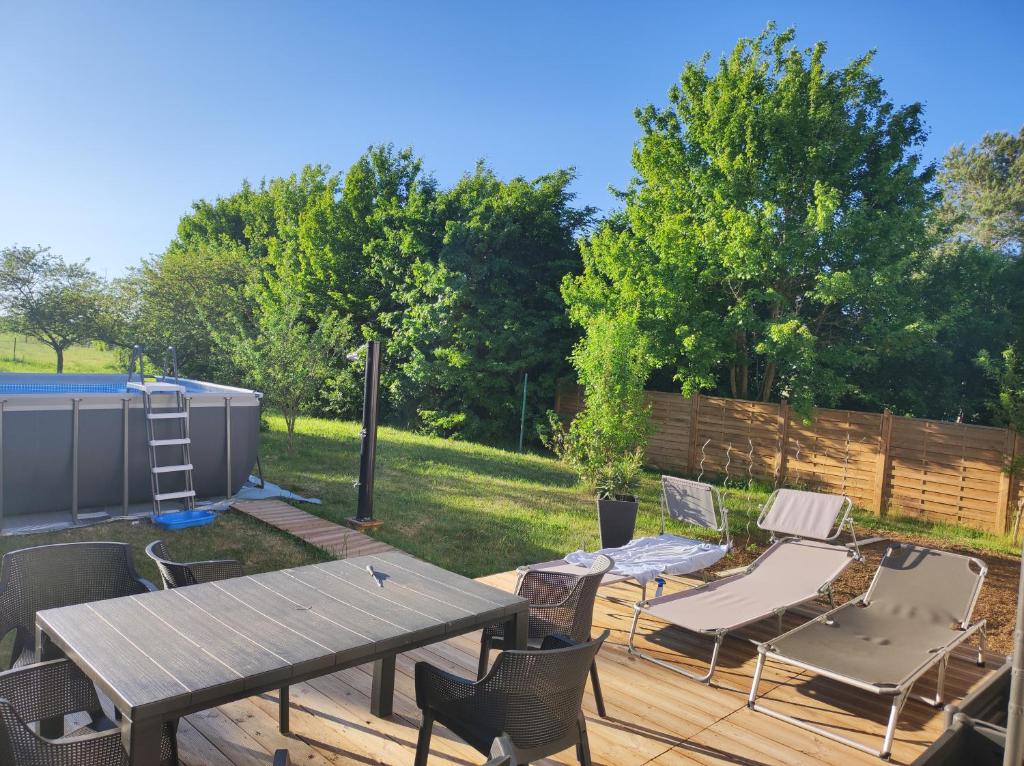 una terraza de madera con mesa de picnic y sillas en Chez l'habitant pour naturistes uniquement, nudist only, en Ville-sur-Yron