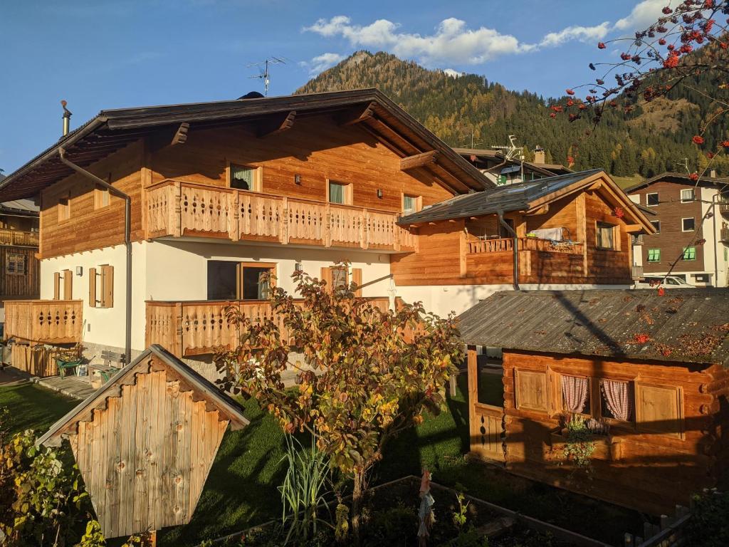ein großes Holzhaus mit einer Veranda und einem Balkon in der Unterkunft Ciasa Giorgina in Pozza di Fassa