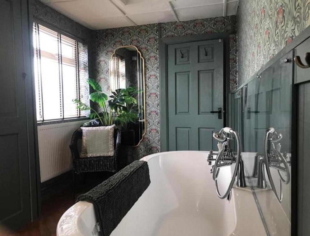 卡馬森的住宿－Pondside Cottage，一间带大型白色浴缸和镜子的浴室