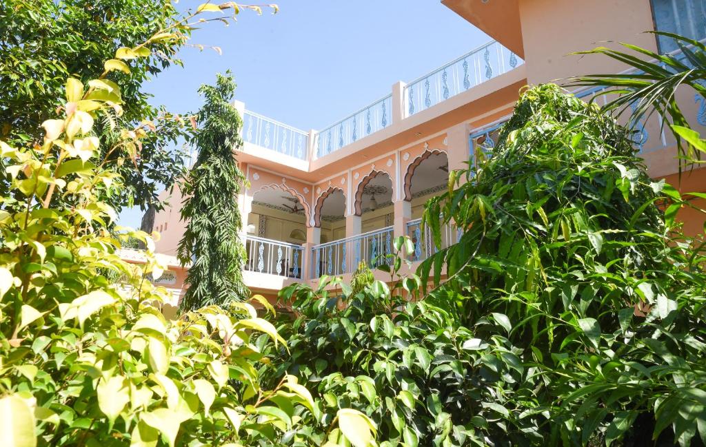 un bâtiment rose avec des arbres devant lui dans l'établissement KothiPushkar, à Pushkar