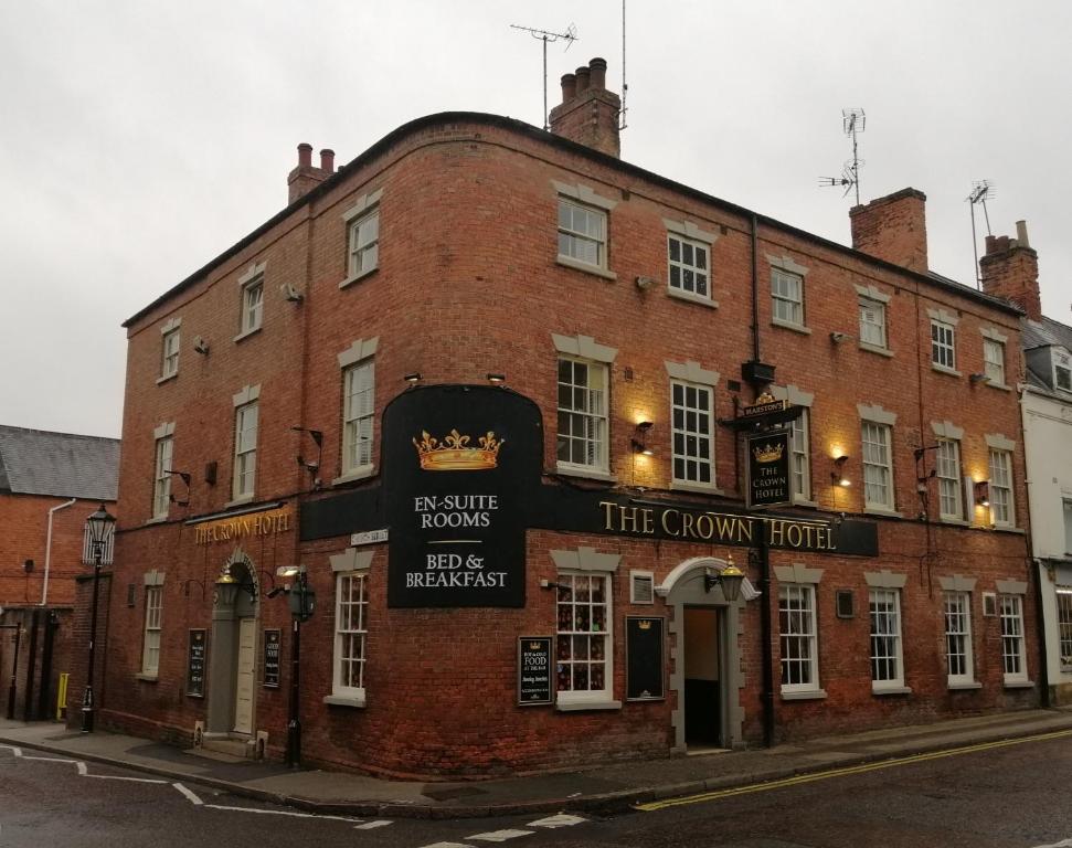 a large red brick building with a sign on it at The Crown Hotel in Southwell