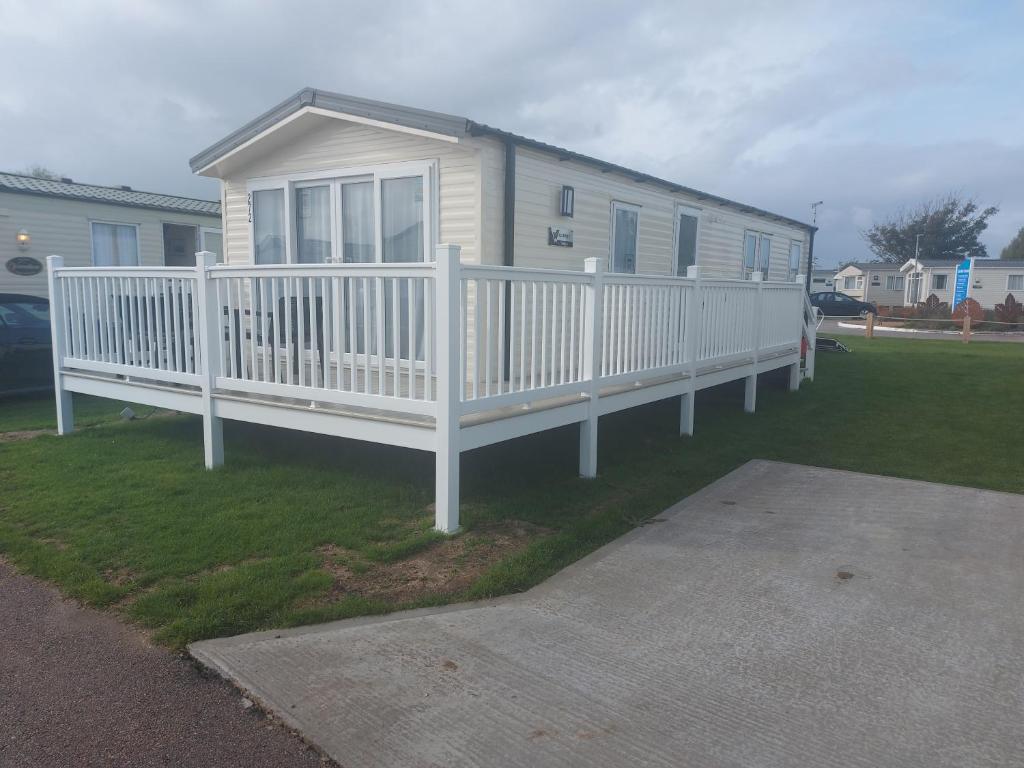 a house with a white fence on a yard at Sophie's Caravan in Camber