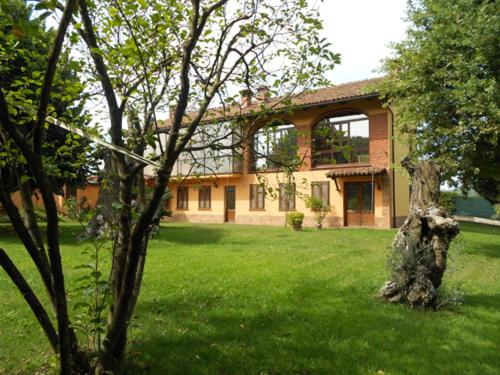 a house with a tree stump in the yard at Cascina tra le vecchie vigne con piscina in Canale