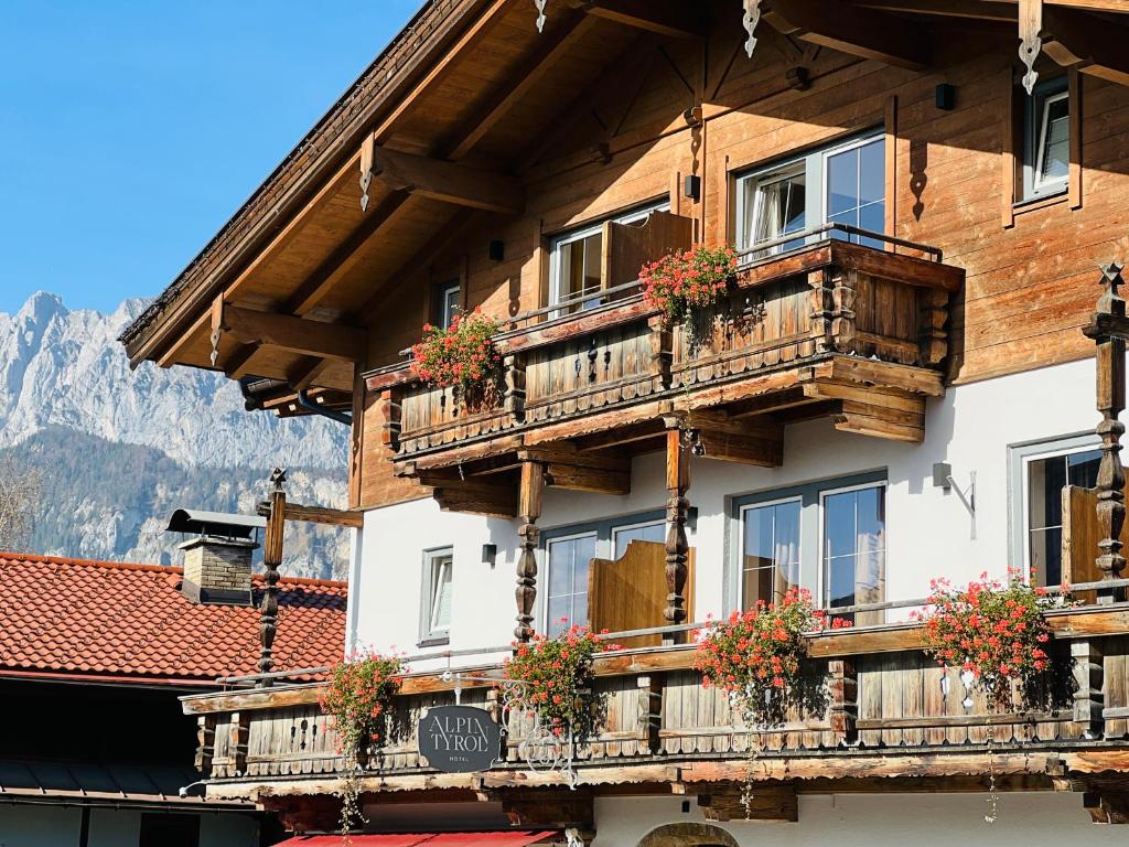 サンクト・ジョアン・イン・チロルにあるHotel Alpin Tyrol - Kitzbüheler Alpenの木製バルコニーと花が飾られた建物