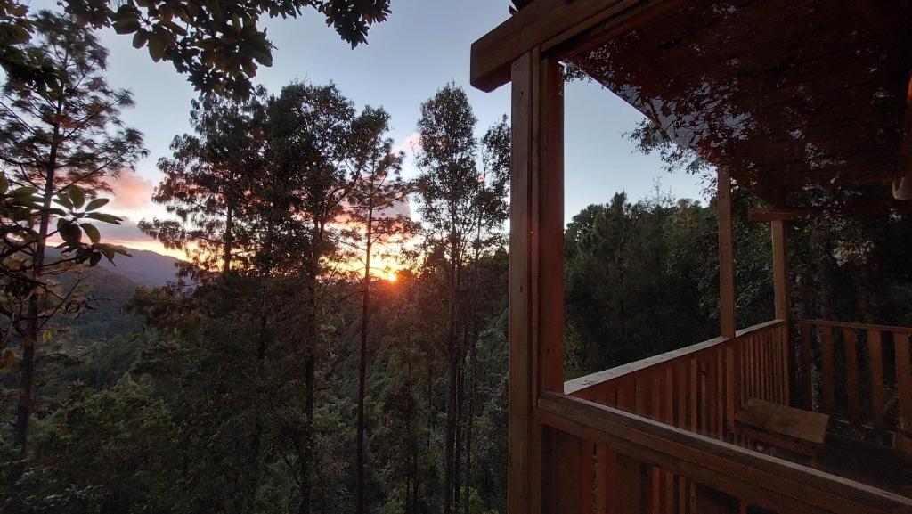 een uitzicht op de zonsondergang vanaf de veranda van een hut bij Cabaña en el Bosque de San José del Pacífico in El Pacífico