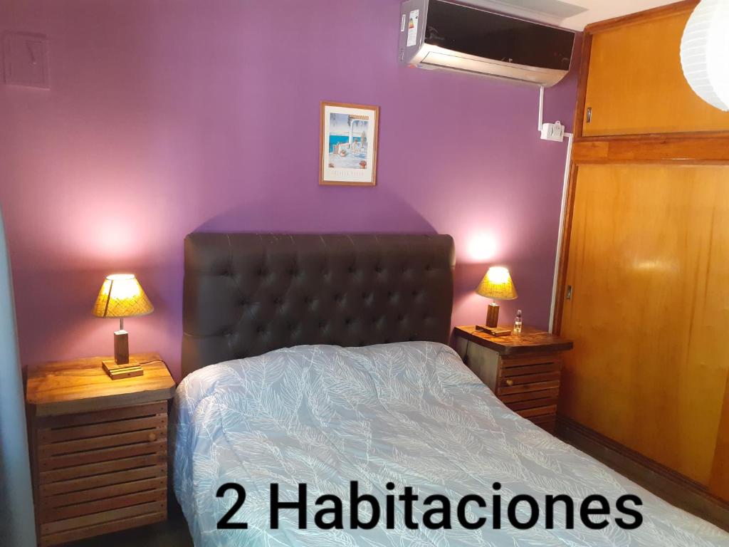 a bedroom with a bed and two night stands with lamps at Cabañas Don Pocho in Villa Cura Brochero
