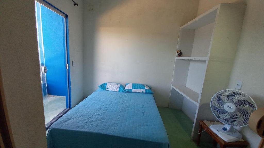 a small room with a bed and a fan at Residencial Praia Quente casas in Nova Viçosa