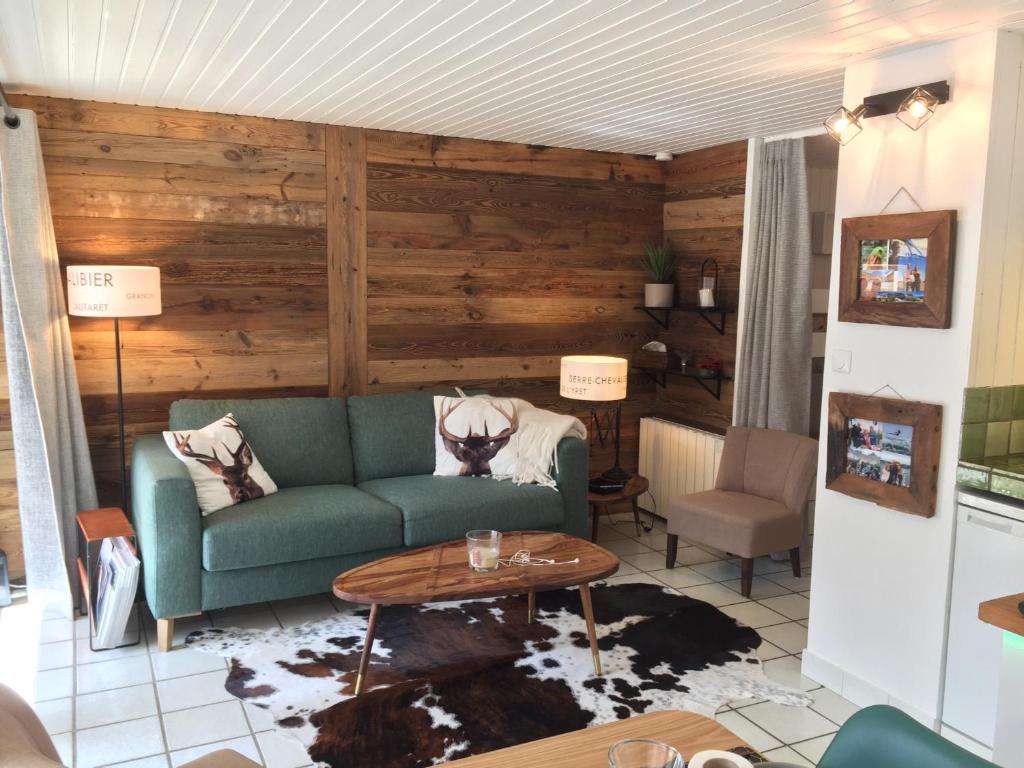un salon avec un canapé vert et une table dans l'établissement Serre Chevalier Chantemerle T2 + coin montagne en RDC pour 6 personnes, à Saint-Chaffrey