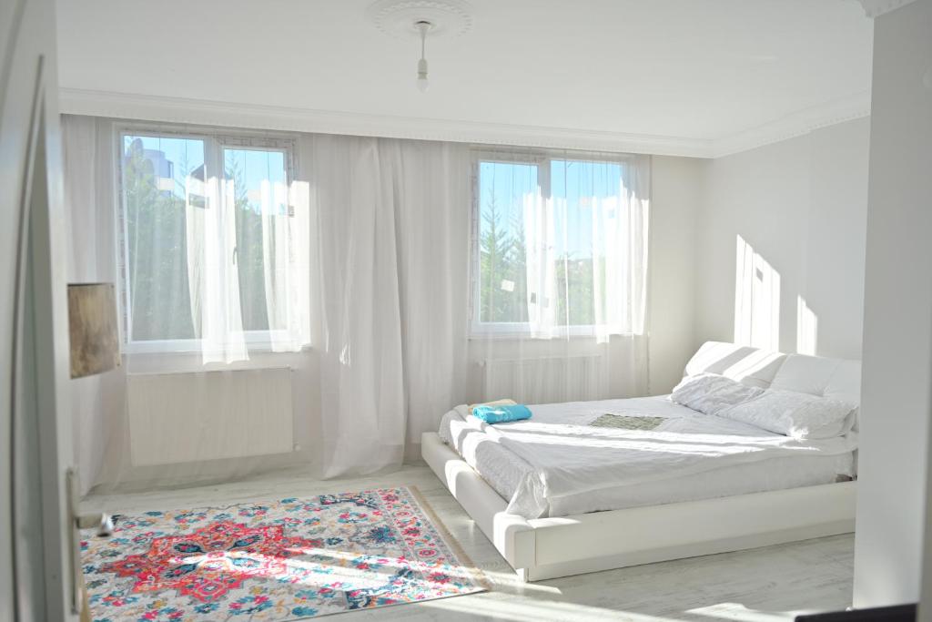 a white bedroom with two beds and a rug at Ahmet teacher's villa, 6 minutes from the airport in Arnavutköy