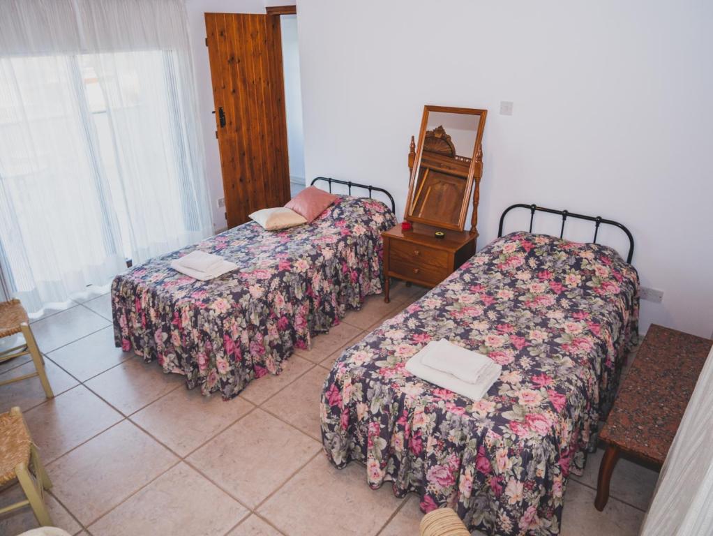 Ayios MamasにあるRevecca Houseのベッド2台、テーブル、鏡が備わる客室です。