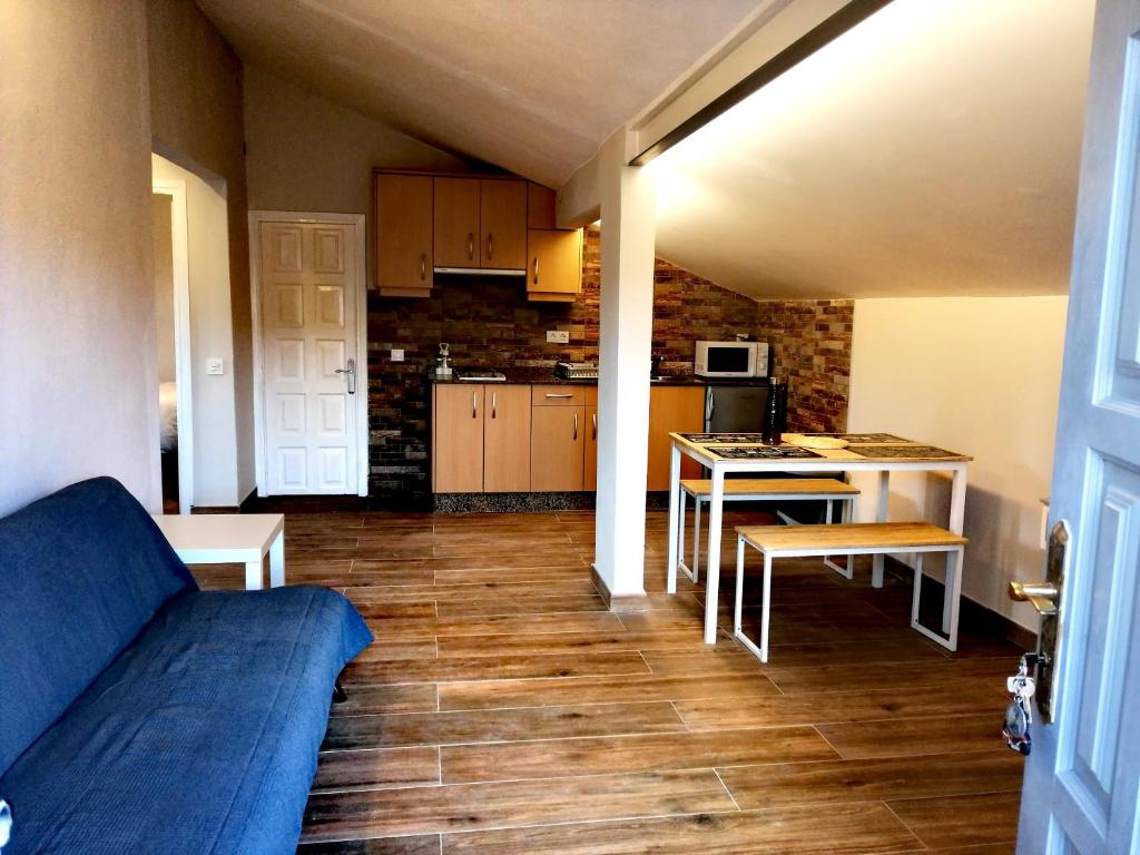 ein Wohnzimmer mit einem blauen Sofa und einer Küche in der Unterkunft El Desván del Chisco in Cudillero