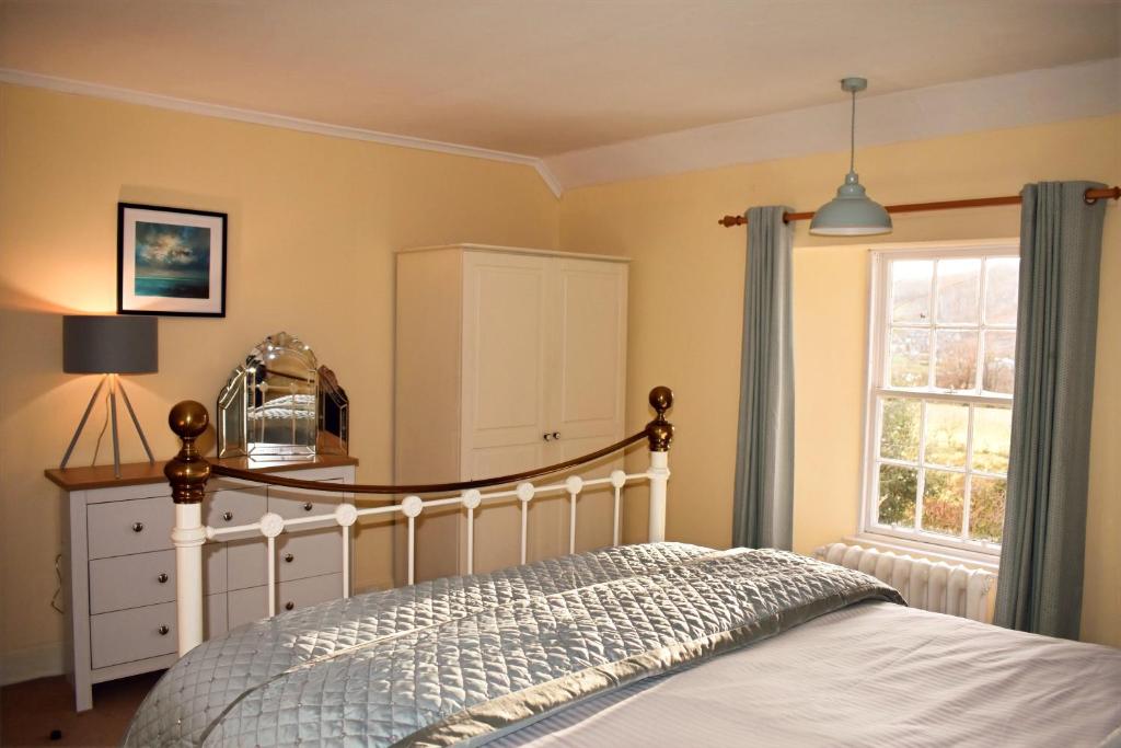 a bedroom with a bed with a dresser and a window at Creran Apartment, Kinlochlaich House in Appin