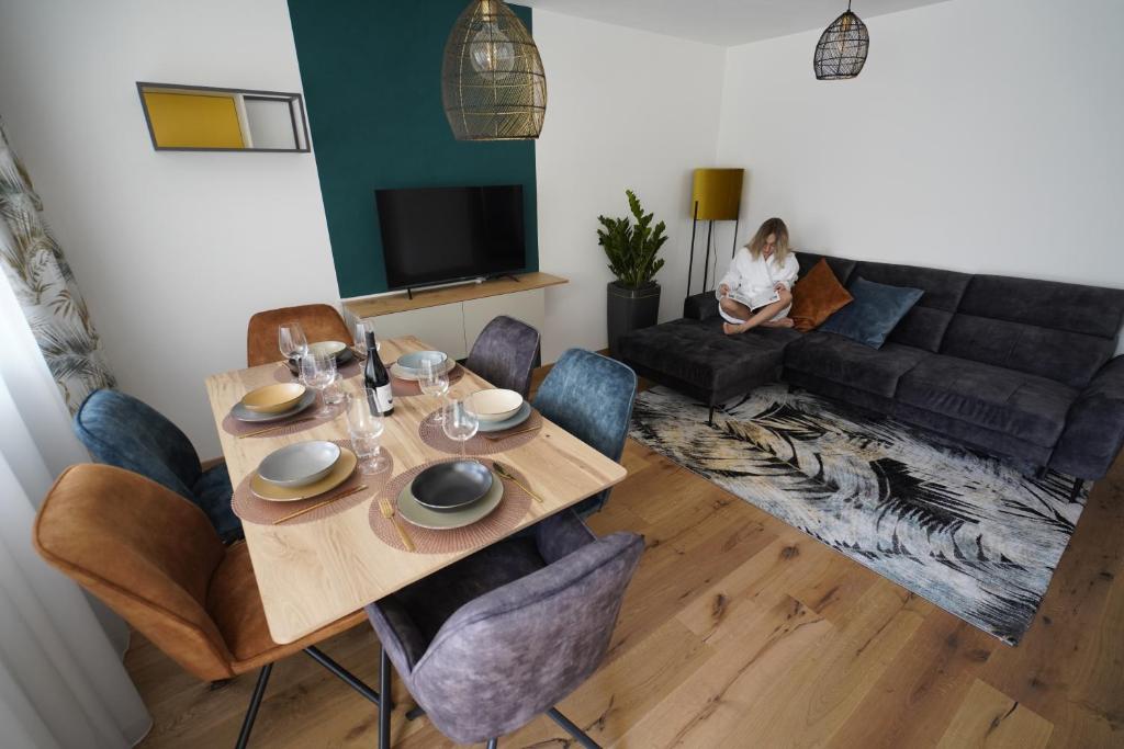 a living room with a table and a woman sitting on a couch at T-Collection Premium Apartments in Vipiteno