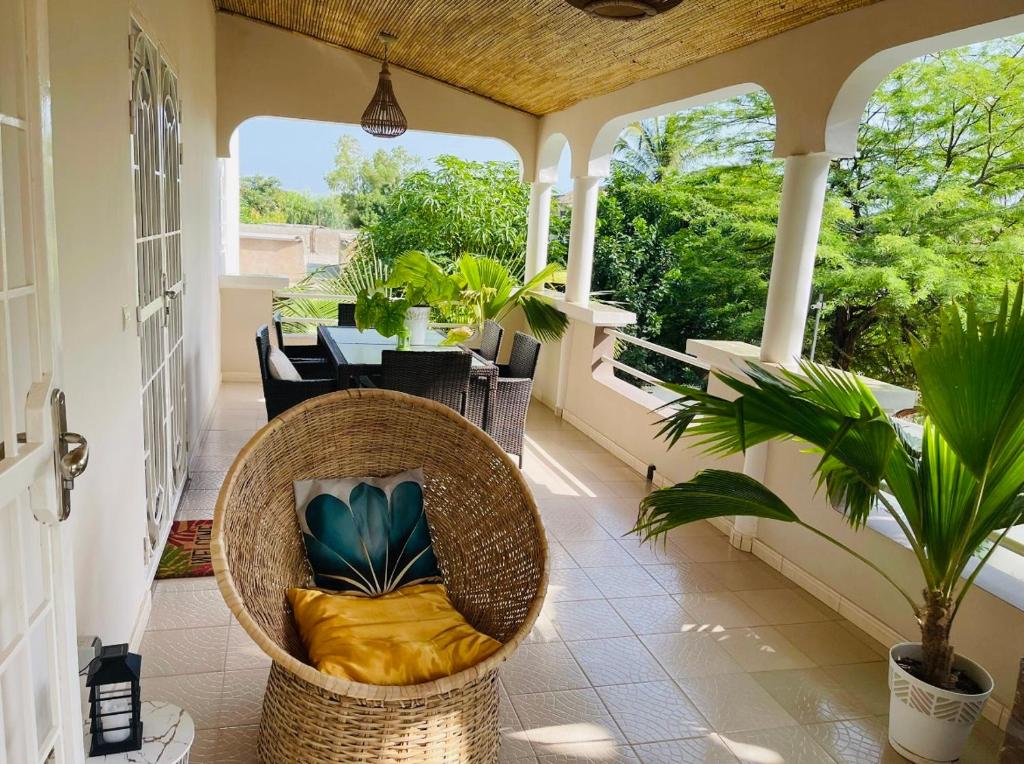 un porche con una silla de mimbre y una mesa en Villa Ngorè Saly, en Saly Portudal