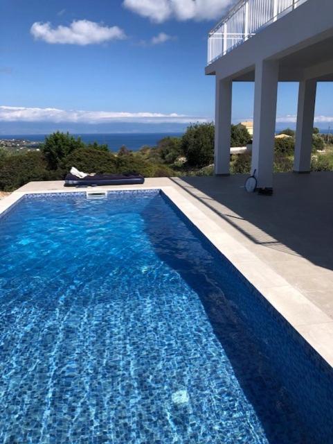 a large blue swimming pool next to a house at Villa Peony Koroni in Koroni