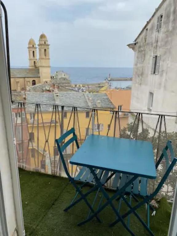 une table bleue sur un balcon avec vue sur un bâtiment dans l'établissement Côté Vieux Port, à Bastia