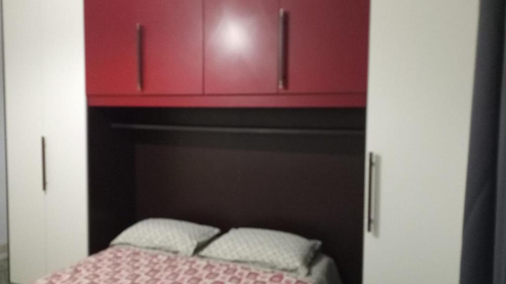 a small room with a bed and red cabinets at Federica House in Bologna