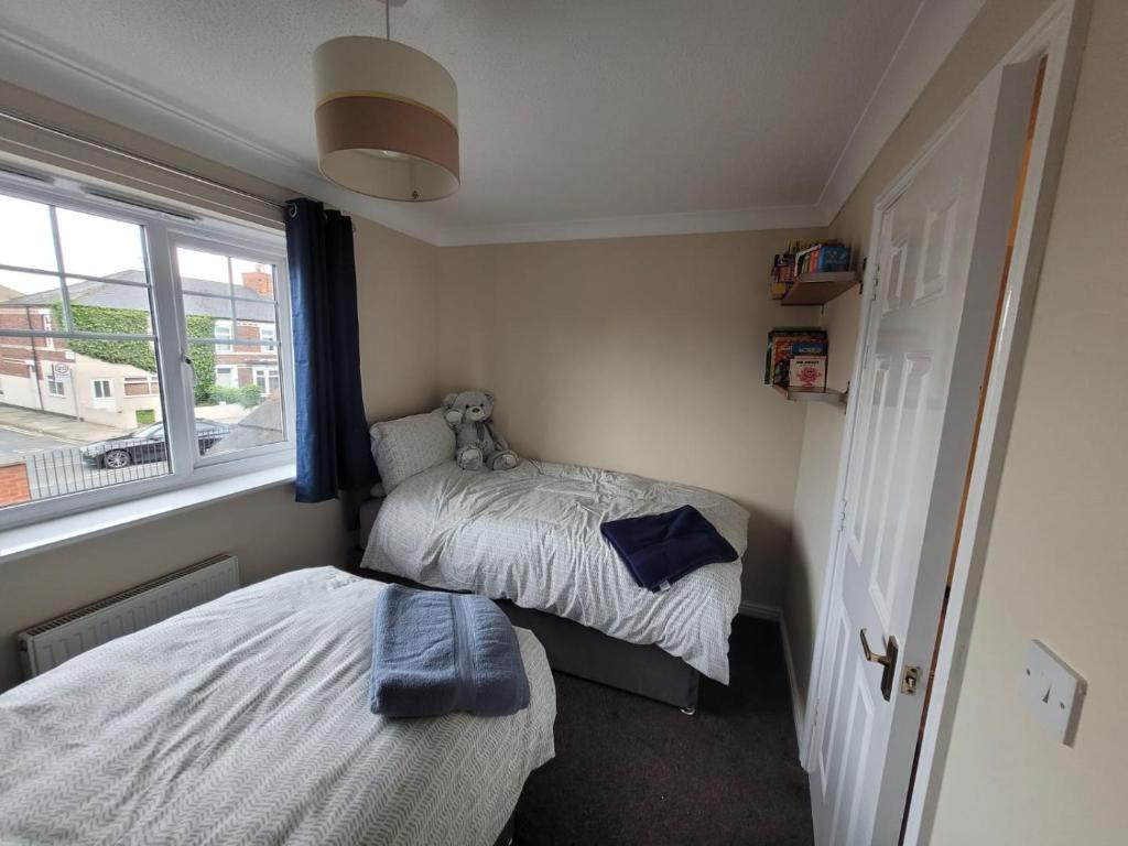 two beds in a small room with a window at Cosy 3 bedroomed home on 3 floors in Darlington