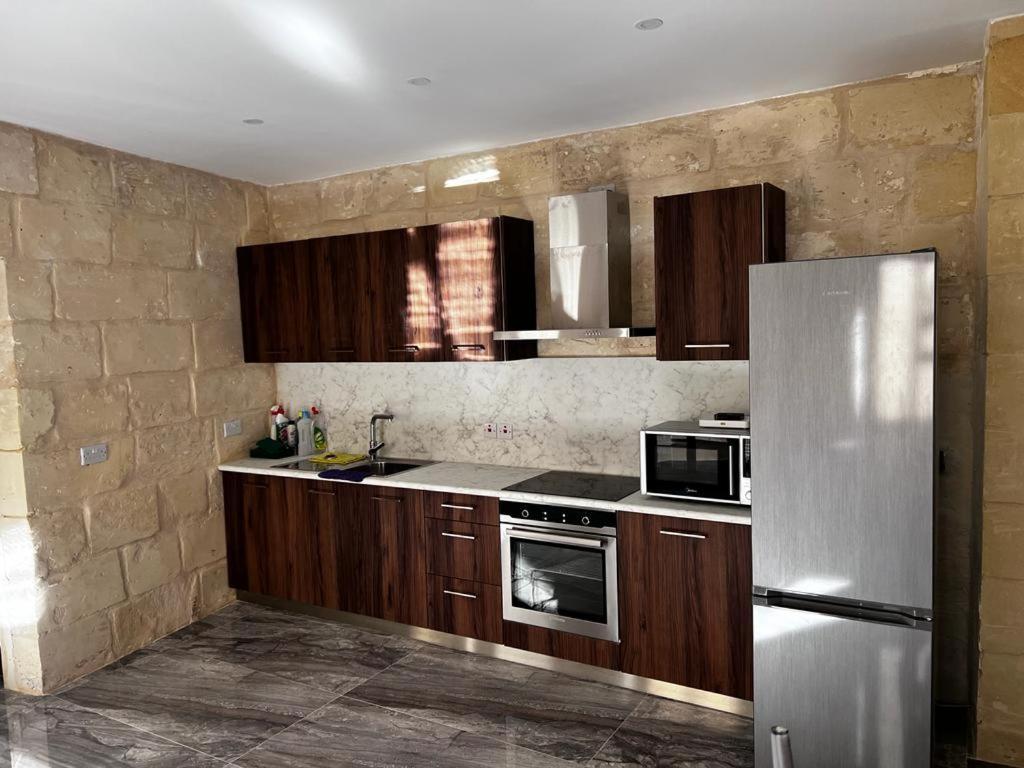 a kitchen with wooden cabinets and a stainless steel refrigerator at L-irdoss in Vittoriosa