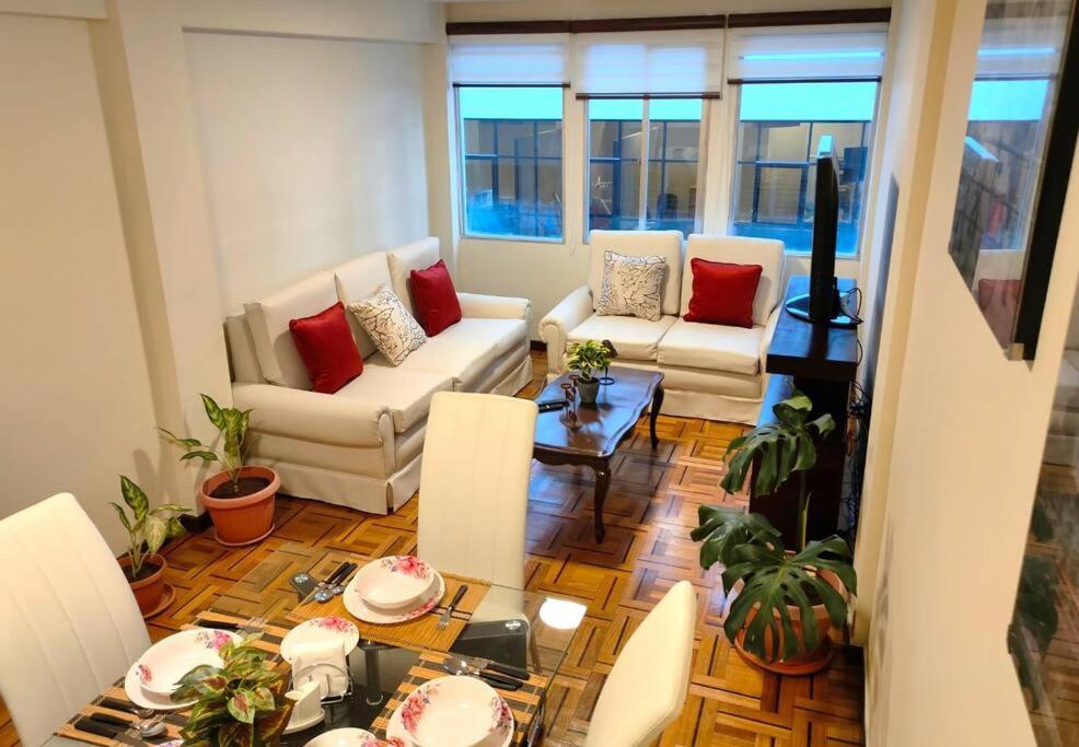una sala de estar con muebles blancos y almohadas rojas. en Cómodo, amplio y céntrico apartamento en Sopocachi en La Paz