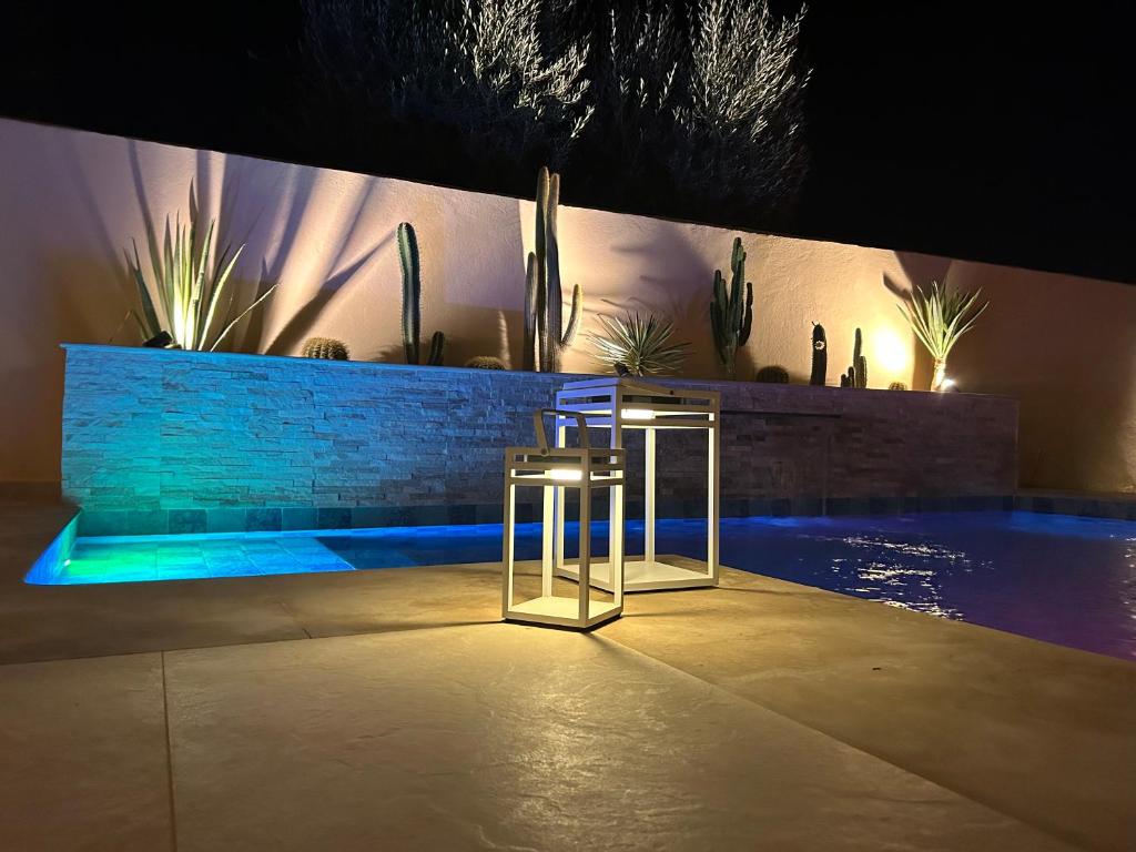 a pair of stools next to a pool at night at Villa Nawal et sa piscine chauffée sans vis-à-vis in Agadir