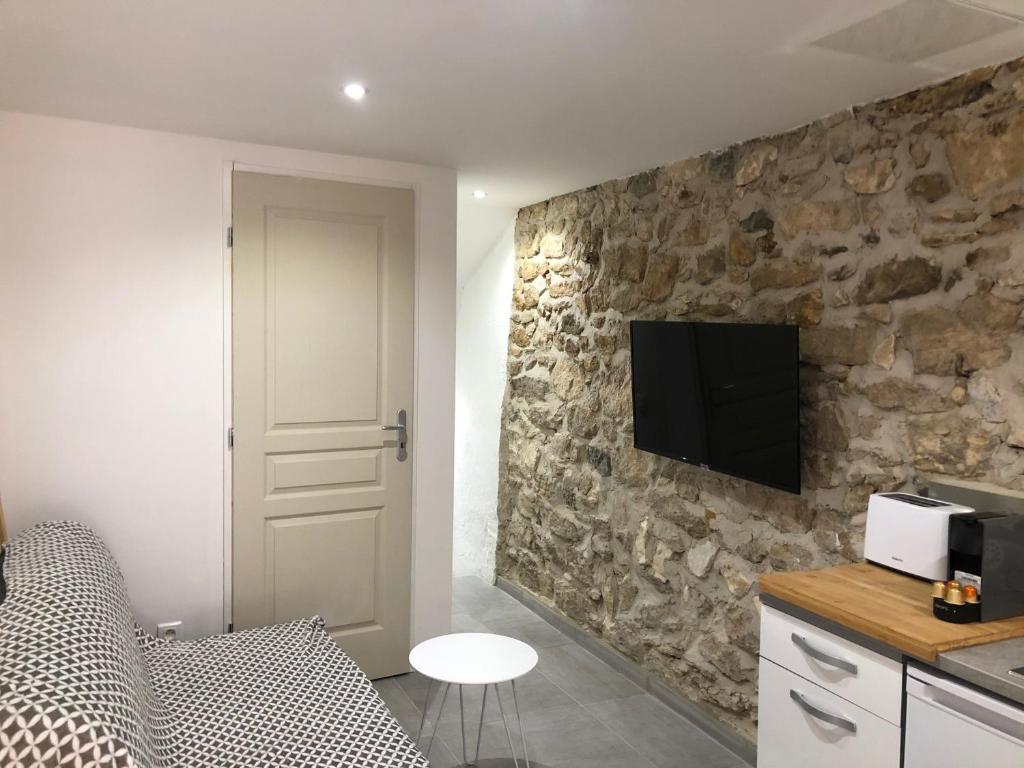 - une chambre dotée d'un mur en pierre et d'une télévision dans l'établissement Les Olives Wifi Netflix Appart-hotel-Provence, à La Fare-les-Oliviers