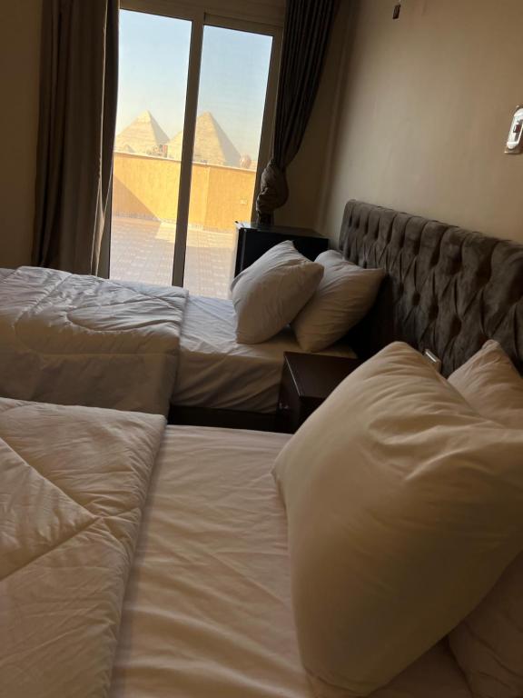 2 camas en una habitación de hotel con vistas a las pirámides en Bedouin Pyramids View en El Cairo