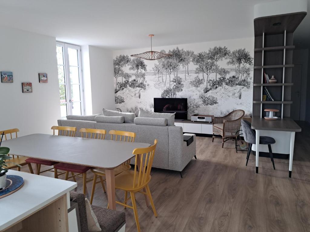 uma sala de estar com um sofá, uma mesa e cadeiras em Superbe appartement T3 au centre plage .Parking em Hendaye