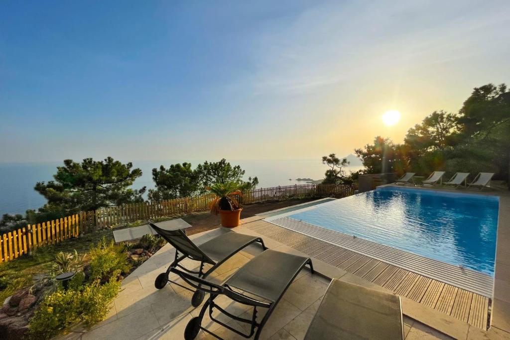 a house with a swimming pool and chairs on a deck at Family villa with magnificent sea view for 11 people in Saint-Raphaël
