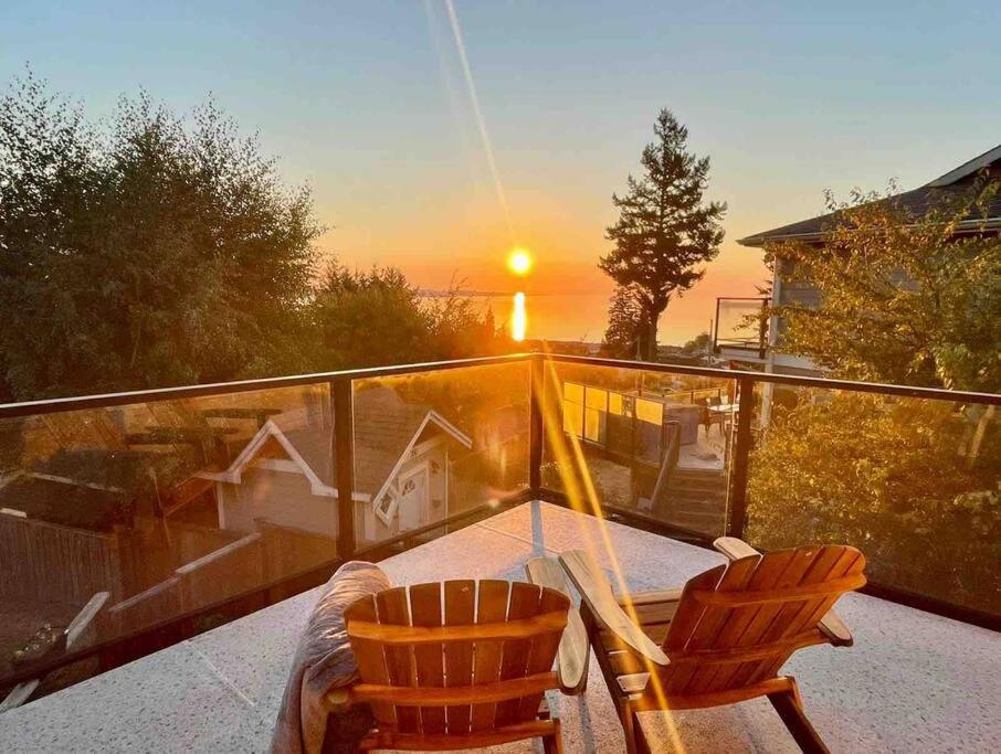 two chairs and a glass table on a balcony with the sunset at Sunrise Escape - Close to the BEACH! in Victoria