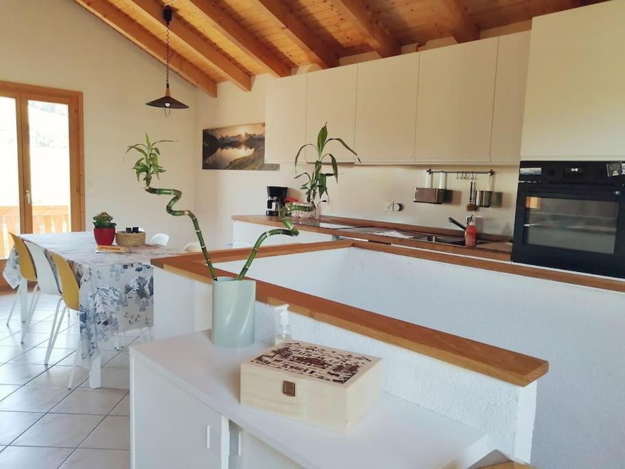 una cucina con bancone bianco e tavolo di Confortable chalet avec magnifique vue en Gruyère. a Charmey