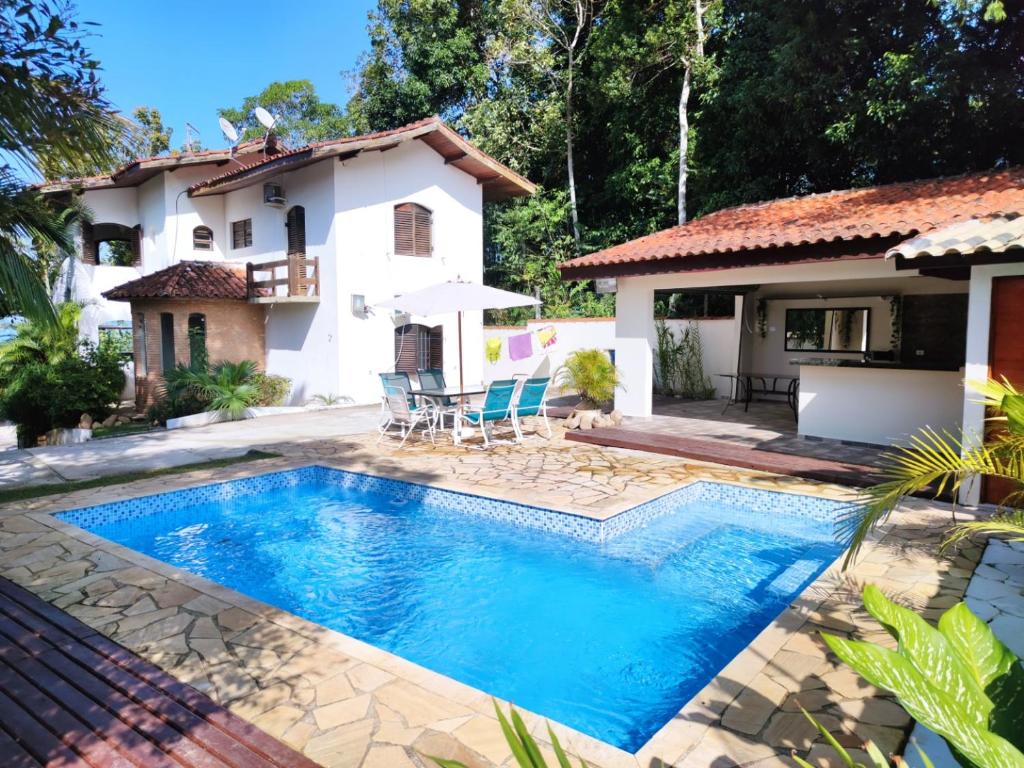 a swimming pool in front of a house at Casa da Cocanha COND com PISCINA-SINUCA-CHURRASQ-DECK com vista para o mar in Caraguatatuba