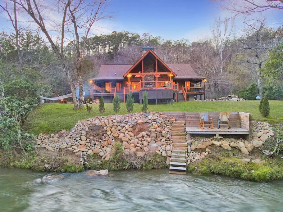 une grande maison avec une rivière en face dans l'établissement Ruby River Lodge, à Ellijay